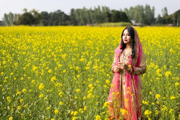 Beautiful south east asian girl in traditional Indian sari/saree on canola oil plants background.