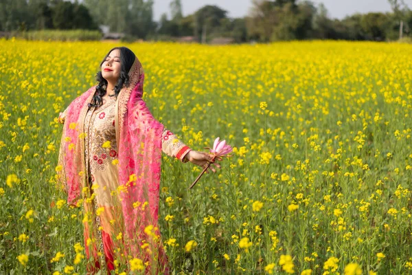 Beautiful south east asian girl in traditional Indian sari/saree on canola oil plants background.