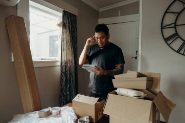 Satıcı olarak dövmesi olan bir adam teslimat kutusunu müşteri için hazırlar, çevrimiçi satışlar, ya da ekommerce. Çevrimiçi alışveriş kavramları. Sipariş kontrol ediliyor.