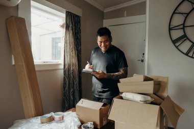 Satıcı olarak dövmesi olan bir adam teslimat kutusunu müşteri için hazırlar, çevrimiçi satışlar, ya da ekommerce. Çevrimiçi alışveriş kavramları. Sipariş kontrol ediliyor.