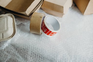 Müşteri için teslimat kutusunun ayarlanması, çevrimiçi satışlar, kutu, bant ve plastik baloncuklar ahşap masada. Online alışveriş kavramları.