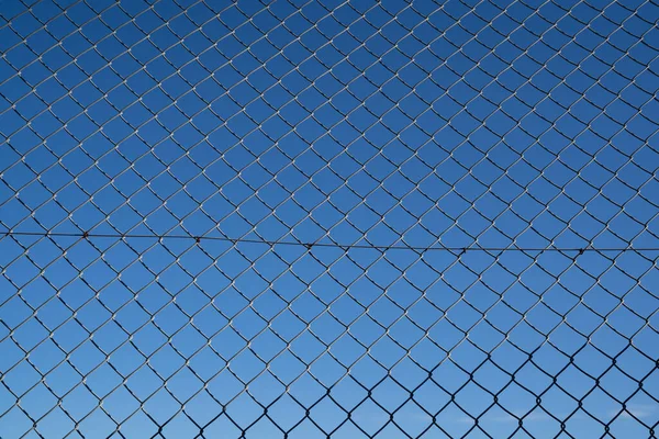Steel mesh wire fence with blue sky under blue sky.