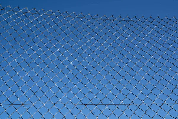 Steel mesh wire fence with blue sky under blue sky.