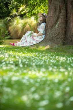 Parktaki ağacın altında oturan güzel Asyalı kadın..
