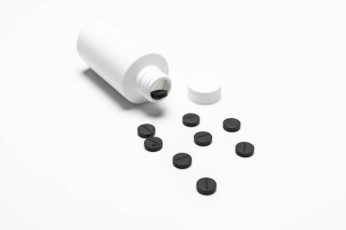 İçinde ilaç olan beyaz bir şişe. Beyaz arka planda haplar ya da tabletler. Kopyalama alanı.