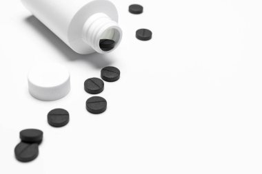 İçinde ilaç olan beyaz bir şişe. Beyaz arka planda haplar ya da tabletler. Kopyalama alanı.