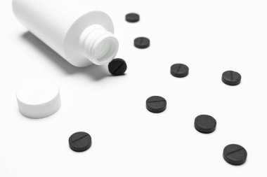 İçinde ilaç olan beyaz bir şişe. Beyaz arka planda haplar ya da tabletler. Kopyalama alanı.