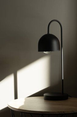 Black lamp on the table with sun light near bed. clipart