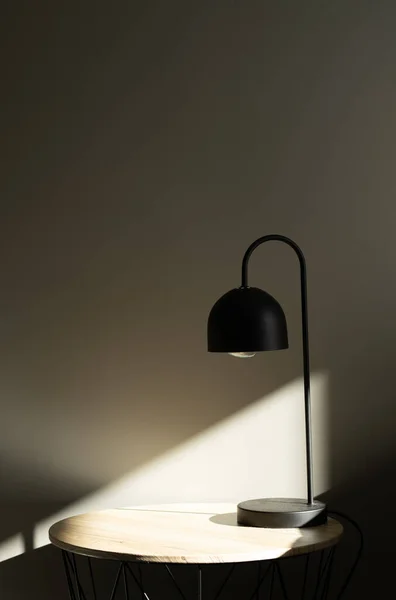 Black lamp on the table with sun light near bed.