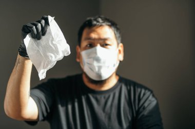 Coronavirus. Tıbbi koruyucu maskeli ve lateks eldivenli bir adam Coronavirus 'u, Covid-19' u, gribi önlemek için kağıt mendil gösteriyor. Sprey şişesi. Virüs ve hastalık koruması.