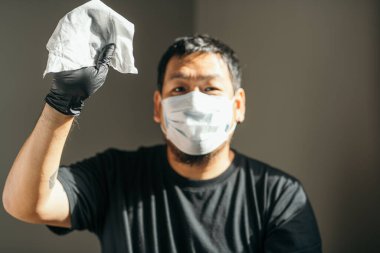 Coronavirus. Tıbbi koruyucu maskeli ve lateks eldivenli bir adam Coronavirus 'u, Covid-19' u, gribi önlemek için kağıt mendil gösteriyor. Sprey şişesi. Virüs ve hastalık koruması.