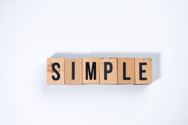 " SIMPLE " text made of wooden cube on  White background.