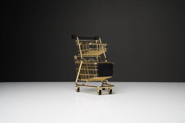 Beyaz masanın üstünde altın renkli küçük boş alışveriş arabası veya metal tramvay ve fotokopi alanı olan koyu arkaplan.