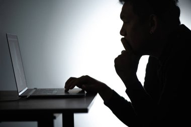 Laptop 'ta çalışan Asyalı siluet adam. Beared Man, Notebook 'ta evden çalışıyor. Serbest çalışan blogcu adam dizüstü bilgisayarla evde çalışıyor. Bakan ve düşünen bir adam.