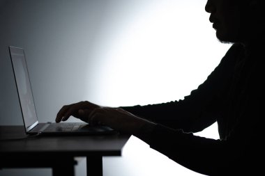 Laptop 'ta çalışan Asyalı siluet adam. Beared Man, Notebook 'ta evden çalışıyor. Serbest çalışan blogcu adam dizüstü bilgisayarla evde çalışıyor. Bakan ve odaklanan bir adam.