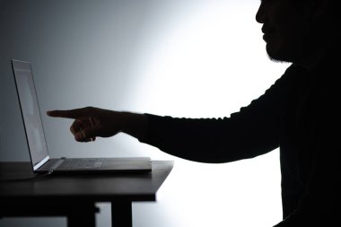 Laptop 'ta çalışan Asyalı siluet adam. Beared Man, Notebook 'ta evden çalışıyor. Serbest çalışan blogcu adam dizüstü bilgisayarla evde çalışıyor. Bakan ve işaret eden bir adam.