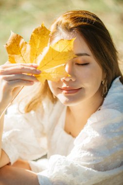 Sonbahar yapraklı, çiçekli ve sonbahar sarısı yapraklı güzel Asyalı kadın Hagley Park, Christchruch, Yeni Zelanda.