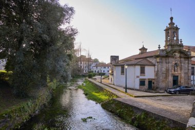 Yürüyüş yolu ve Carmen kilisesi olan Rio Sarela Parkı. Görüntü Santiago de Compostela şehrinde gün batımında..