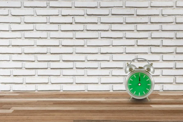 Stalen horloge op houten vloer en bakstenen muur — Stockfoto