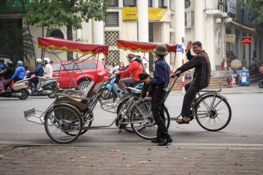 Hanoi, Vietnam - 22 Şubat 2020: Müşteri bekleyen iki Vietnamlı adam, turistler arasında çok popüler bir traktör.