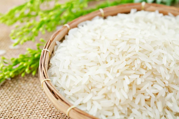 Arroz blanco crudo y cuchara de madera en cesta de tejido . — Foto de Stock