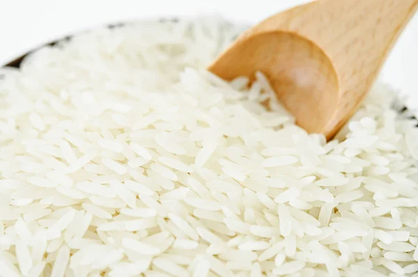 Arroz branco cru e colher de madeira na tigela . — Fotografia de Stock