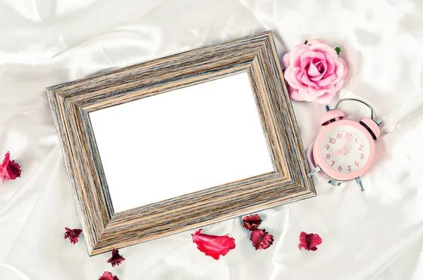 空白的木制图片框架和粉色闹钟与玫瑰. — 图库照片