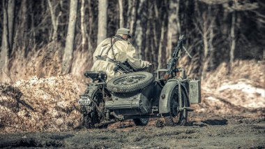 Motosikletli bir Alman askeri çamurun içinden geçiyor. Askeri tarihi yeniden yapılanma.
