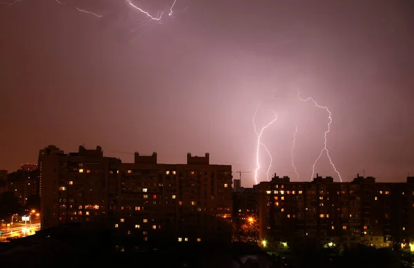 Thunderstorms in the city, lightning in the night sky, lights in the Windows of the house.
