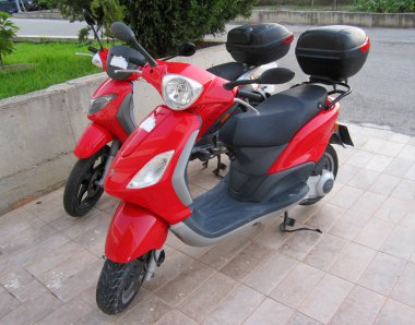 Park yerinde kırmızı bir scooter var.