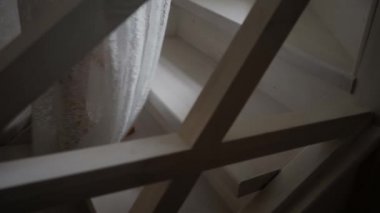 Beyaz cüppeli kız tahta merdivenlere tırmanıyor.