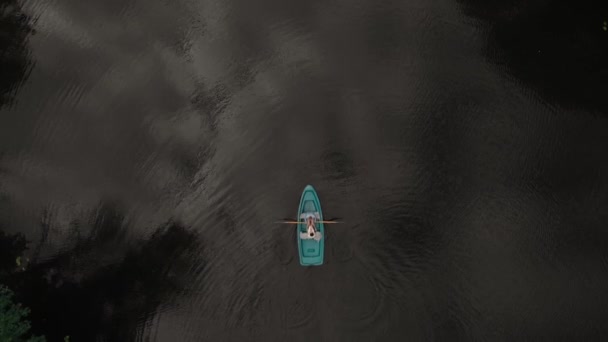 Young man and woman floating on a boat with oars on the forest river. Aerial — Stock Video