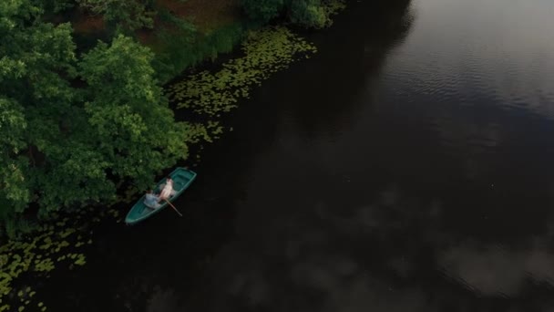 Joven hombre y mujer flotando en un barco con remos en el río bosque. Antena — Vídeos de Stock