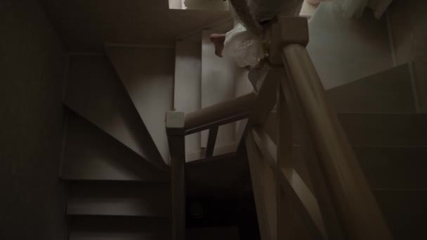 Dívka v bílém rouchu stoupá po dřevěných schodech — Stock video