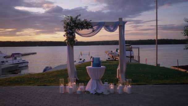 Velmi krásný svatební oblouk a dort při západu slunce na jezeře — Stock video