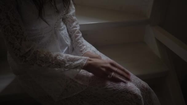 A girl in a white coat sits on the stairs with an engagement ring on her hand — Stock Video