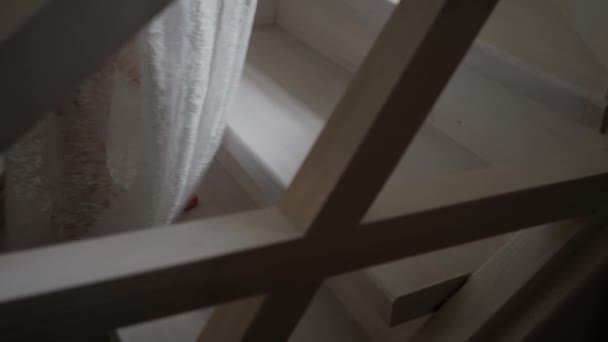 Chica en una bata blanca sube las escaleras de madera — Vídeo de stock