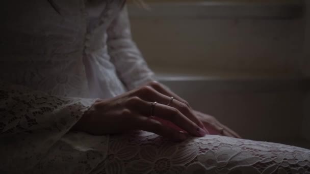 Une jeune fille vêtue d'un manteau blanc est assise dans l'escalier avec un anneau de fiançailles sur la main — Video