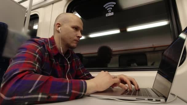 Un joven que trabaja en el tren por la noche en el ordenador . — Vídeo de stock