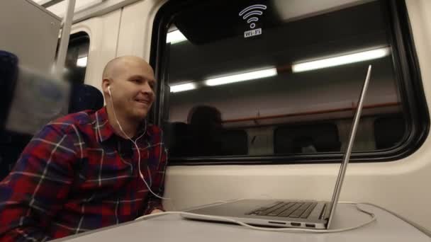 Jongeman aan het praten op de video via de computer terwijl hij in de trein zit. — Stockvideo