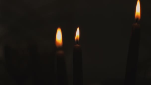 Tres velas encendidas sobre un fondo negro el día de una fiesta religiosa — Vídeos de Stock