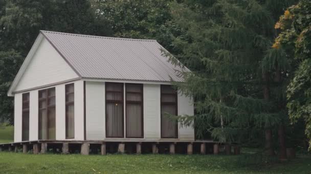 Όμορφο λευκό εξοχικό σπίτι με μεγάλα παράθυρα σε ένα καταπράσινο δάσος — Αρχείο Βίντεο