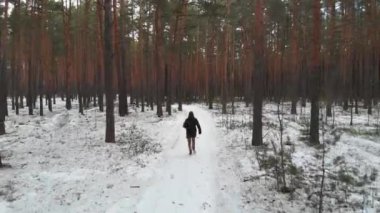 Elinde evrak çantası olan bir adam kış ormanlarında koşuyor. Hava görünümü.