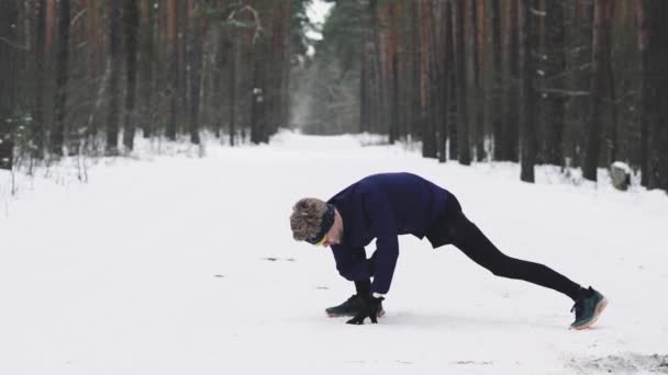 Athlete warms up before Jogging in the woods in winter. Leg warm-up. 4K 50 — Stock video