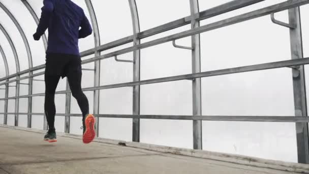 Hombre corriendo en entrenamiento de ropa deportiva antes del triatlón, corriendo en túnel de vidrio . — Vídeos de Stock