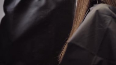 Hair falls in the frame during the haircut process. Hair salon girl haircuts. Close up 4K slow motion