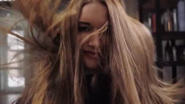 A girl smiles at the camera while her hair is being blow-dried in the salon — Stock Video