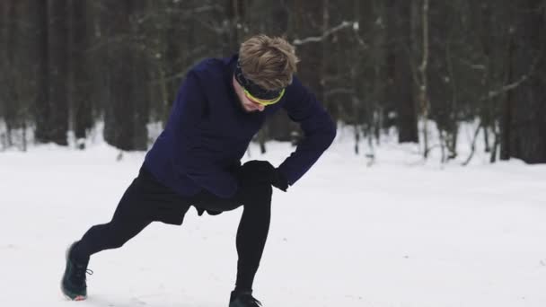 L'athlète se réchauffe avant de faire du jogging dans les bois en hiver. Échauffement des jambes. 4K 50 — Video