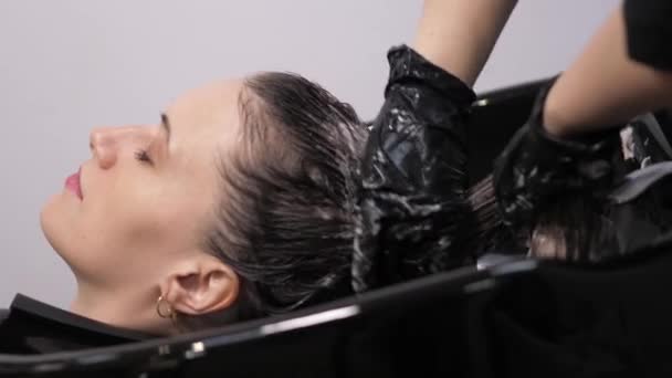 Processo de lavar o cabelo em um cabeleireiro. Menina em um salão de beleza . — Vídeo de Stock