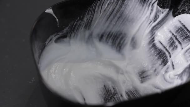 The Barber scoops white paint from a black bowl with a brush. Close up 4K — Stock Video